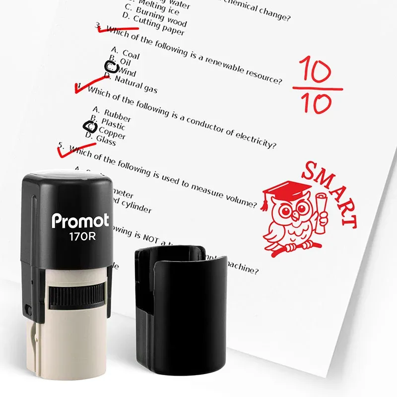 Black self inking stamp and removable cap displayed beside a graded science worksheet marked with red check marks, a “10/10” score, and an owl stamp that says “SMART.” The worksheet includes multiple choice science questions, and this ink stamp for teache
