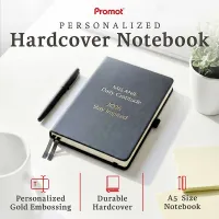 Black hardcover personalized leather journal with custom gold embossed text, displayed on a desk with a pen and plant.