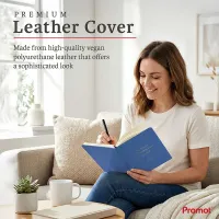 Woman writing in a blue personalized leather journal while relaxing on a sofa, featuring a custom gold embossed cover.