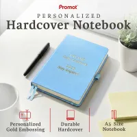 Sky blue notebook with custom gold embossing on a desk beside a pen, a personalized leather journal with a durable hardcover.