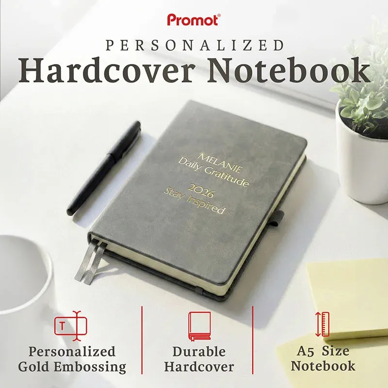 Gray hardcover notebook with gold embossed text on a desk, a personalized leather journal featuring durable A5 design and custom engraving.