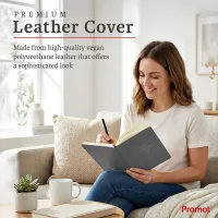 Woman writing in a gray notebook on a sofa, a personalized leather journal with a premium vegan leather cover.