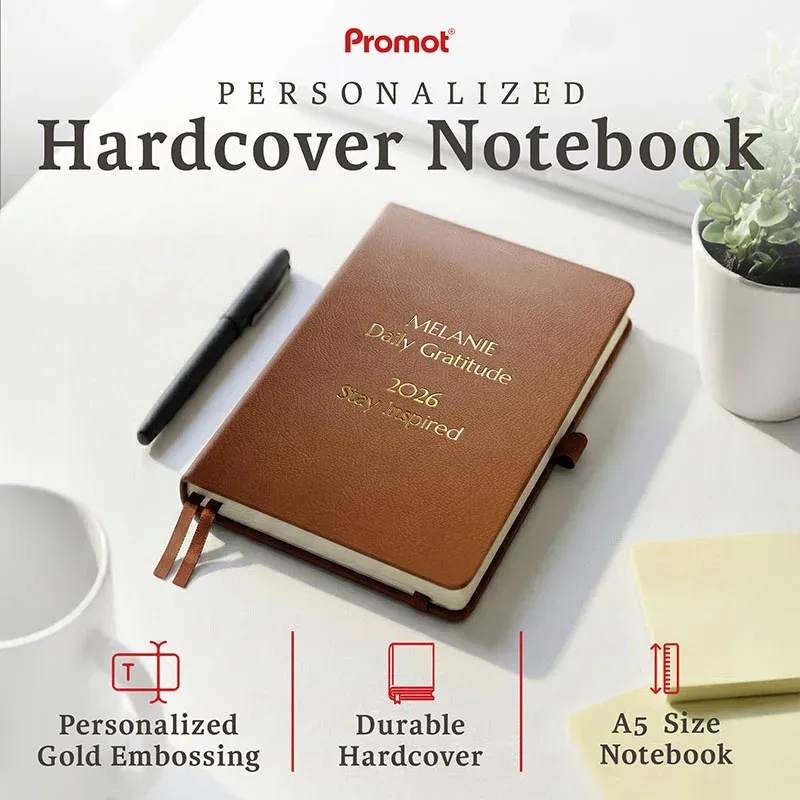 Brown personalized leather journal with custom gold embossed text, displayed on a desk to highlight its durable hardcover and A5 size.