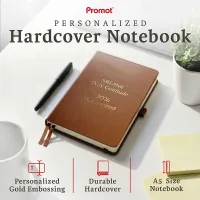 Brown personalized leather journal with custom gold embossed text, displayed on a desk to highlight its durable hardcover and A5 size.