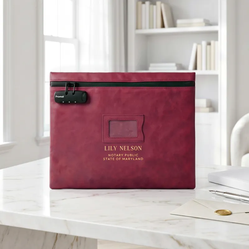 Notary bag with lock in burgundy red, personalized with a gold foil name, on a white marble desk