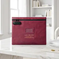 Notary bag with lock in burgundy red, personalized with a gold foil name, on a white marble desk